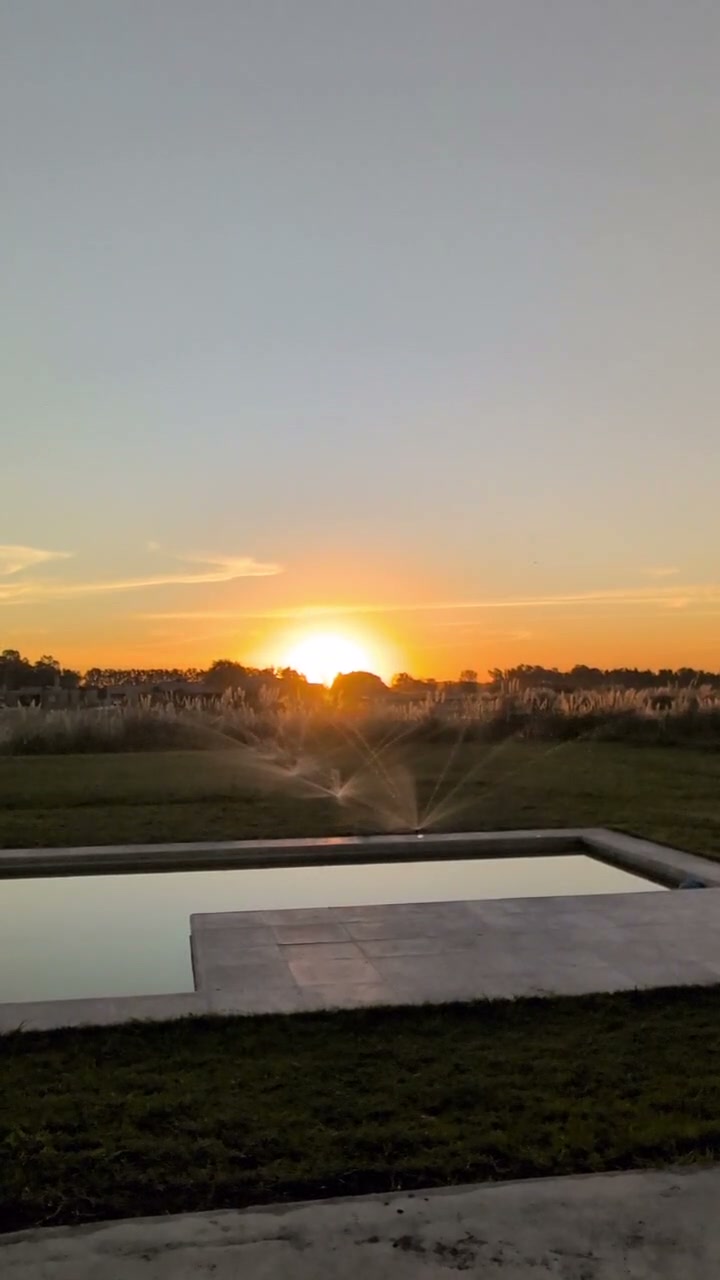 Césped y pileta con riego automático al atardecer